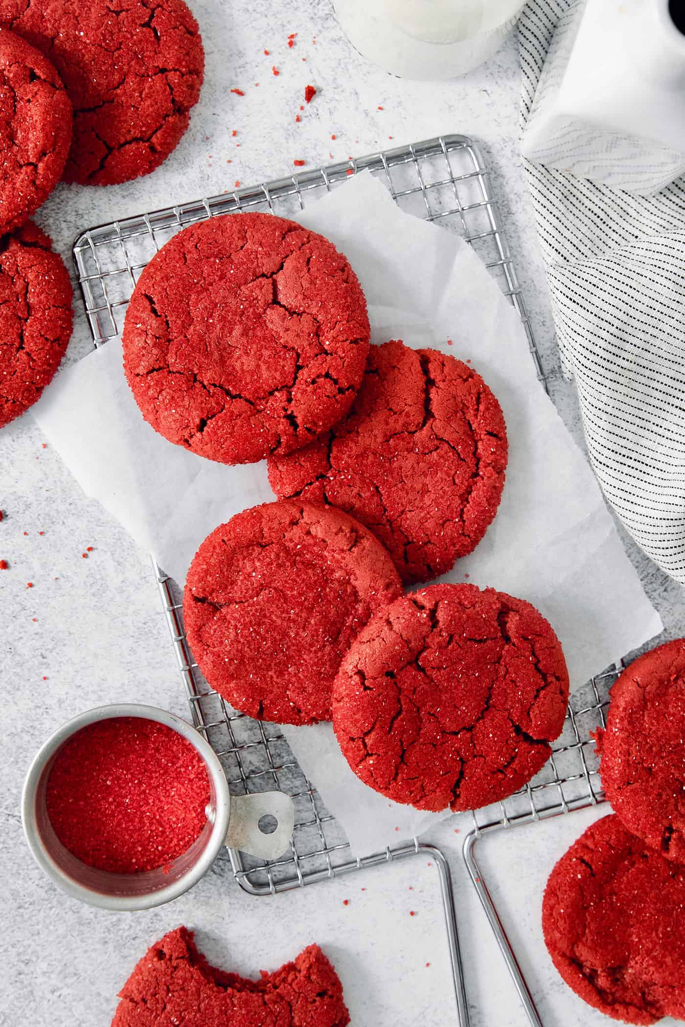 A top down shot of red velvet cookies with a bowl of red sanding sugar next to them.