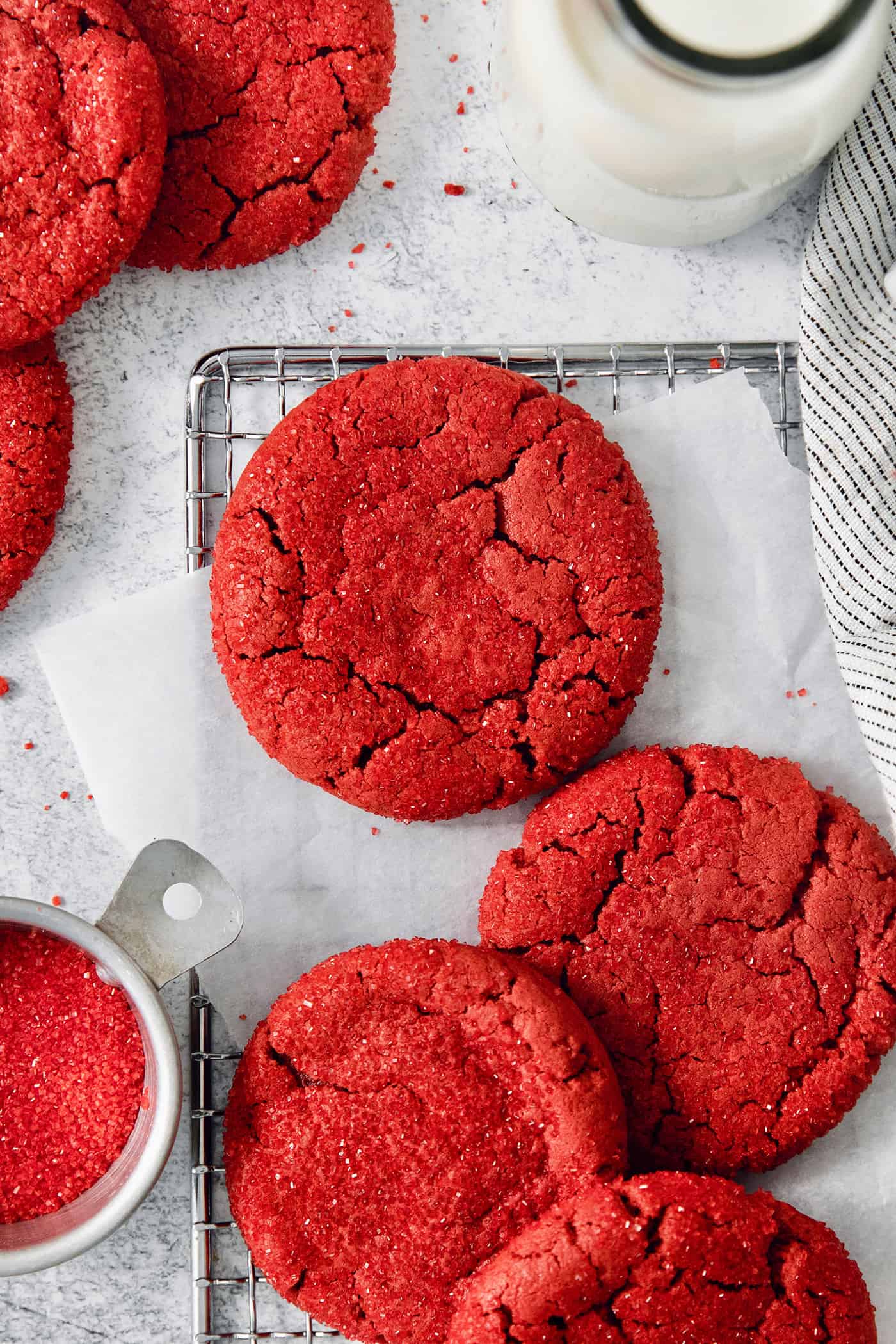 A top down shot of red velvet cookies with a bowl of red sanding sugar next to them.