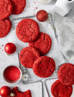 A top down shot of red velvet cookies with a bowl of red sanding sugar next to them.