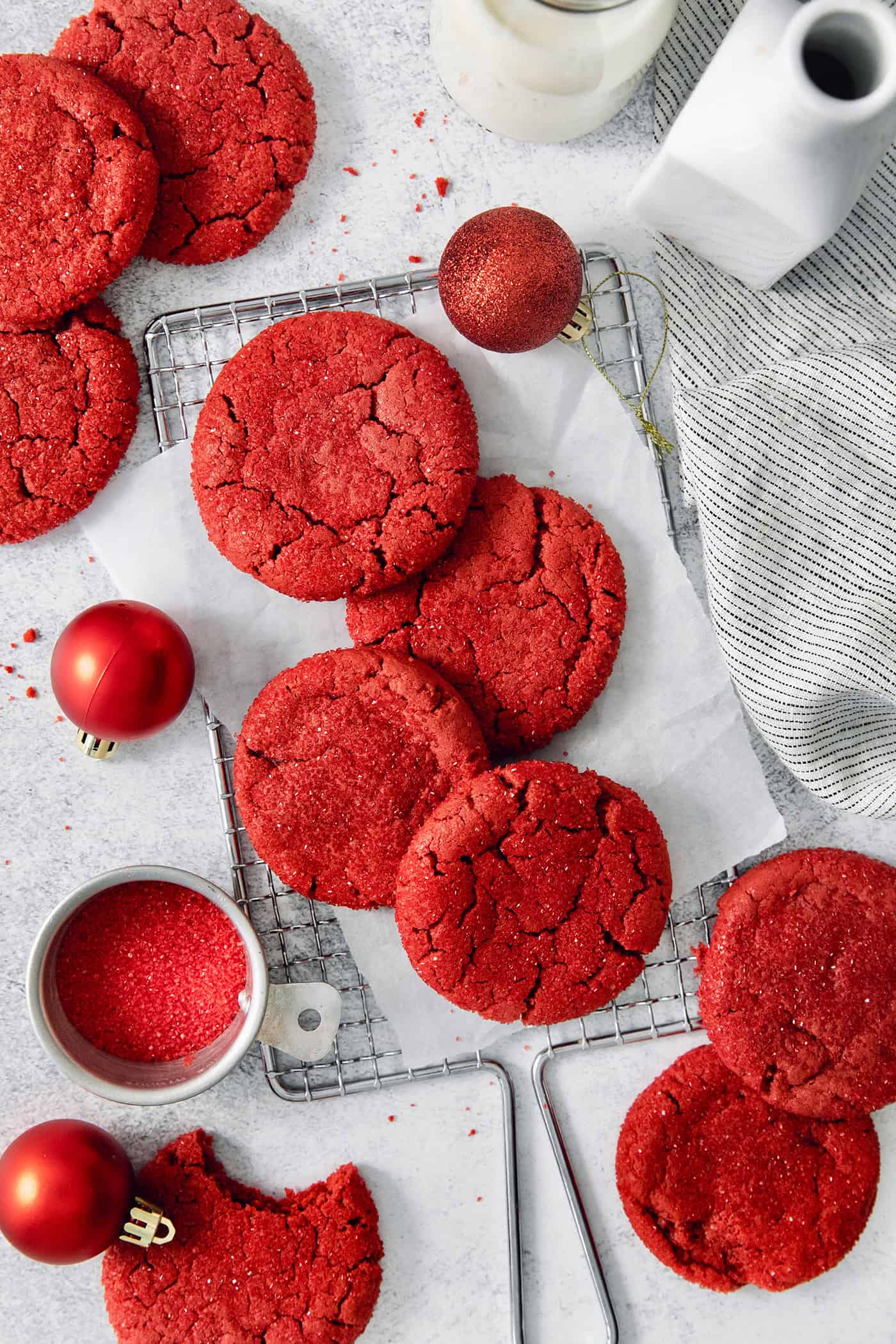 A top down shot of red velvet cookies with a bowl of red sanding sugar next to them.