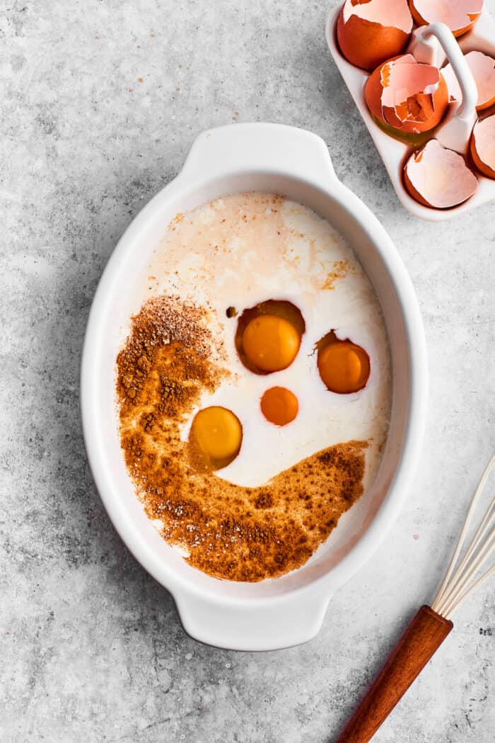 Eggs, milk, cream, and spices are added to a casserole dish for bananas foster French toast.