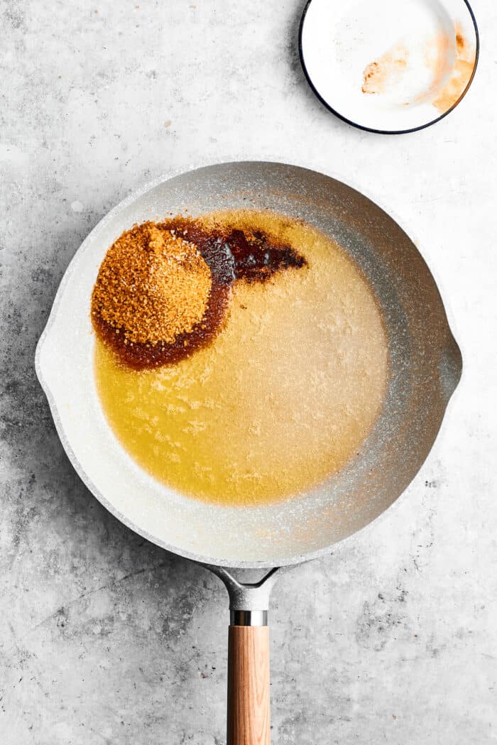 Brown sugar is added to melted butter in a skillet.
