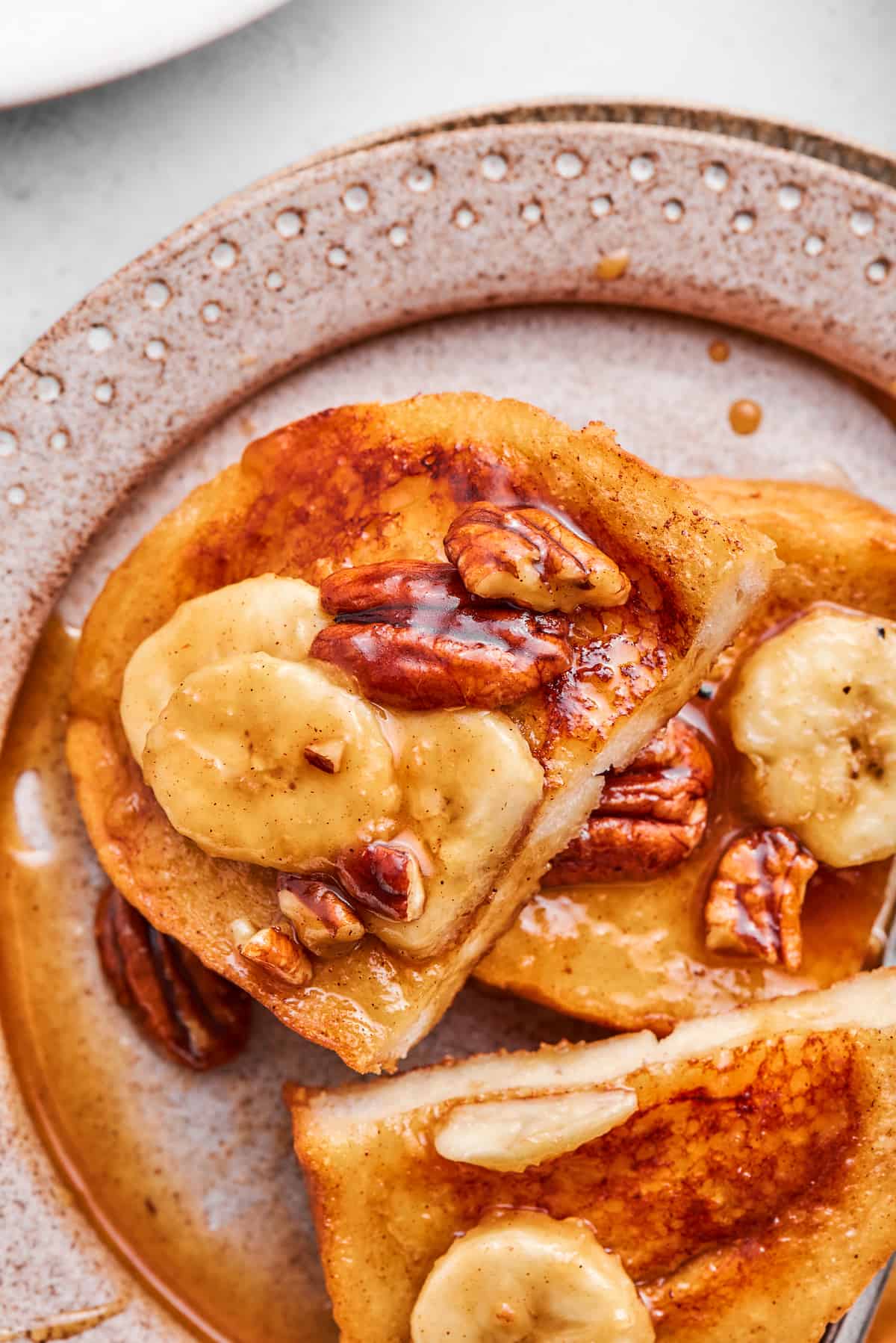 Several slices of bananas foster French toast are shown on a plate.