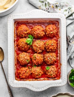 A tray of 12 baked porcupine meatballs with a sprig of parsley.