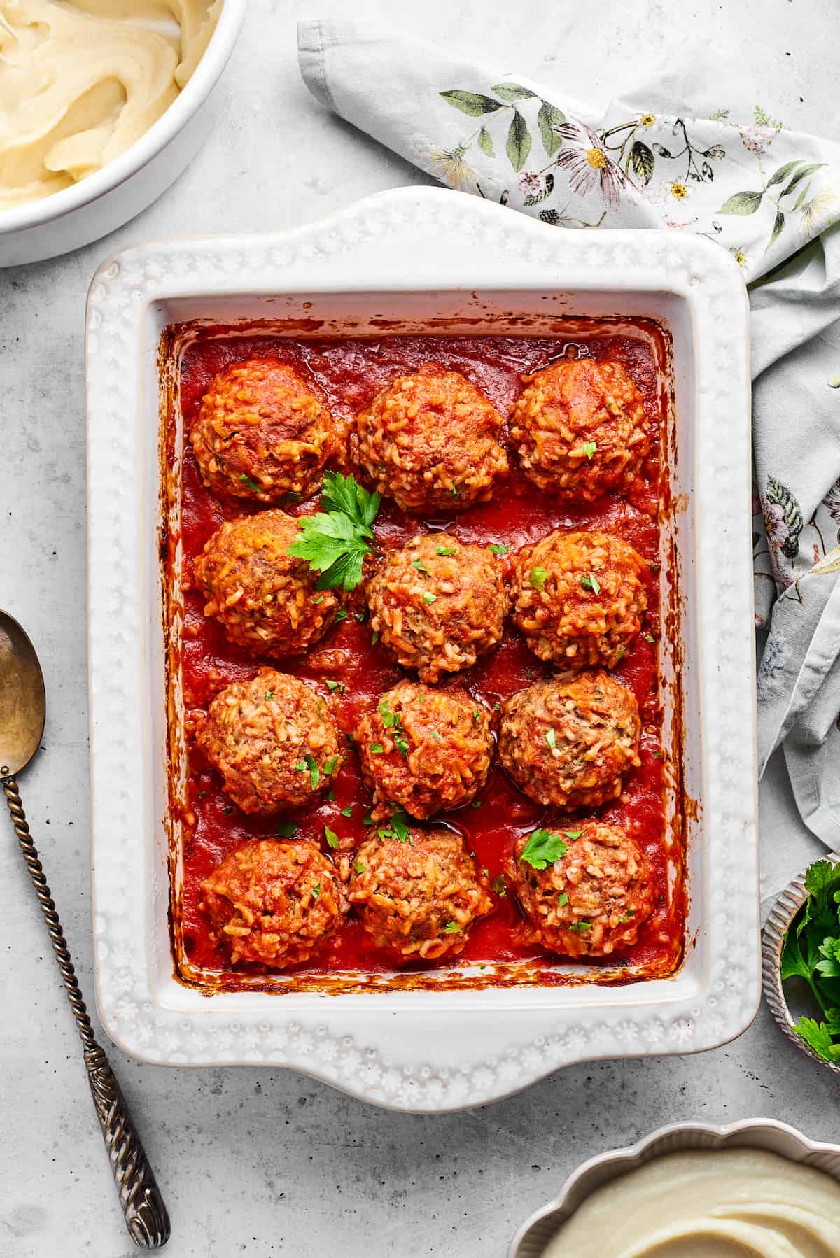 A tray of 12 baked porcupine meatballs with a sprig of parsley.