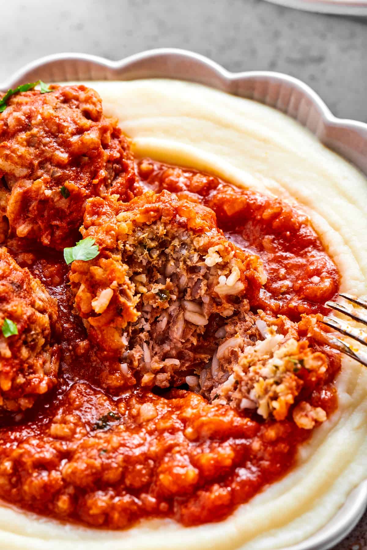 A porcupine meatball is cut in half to show its meat and rice interior.