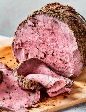 roast beef on a wood cutting boards, with some of it sliced