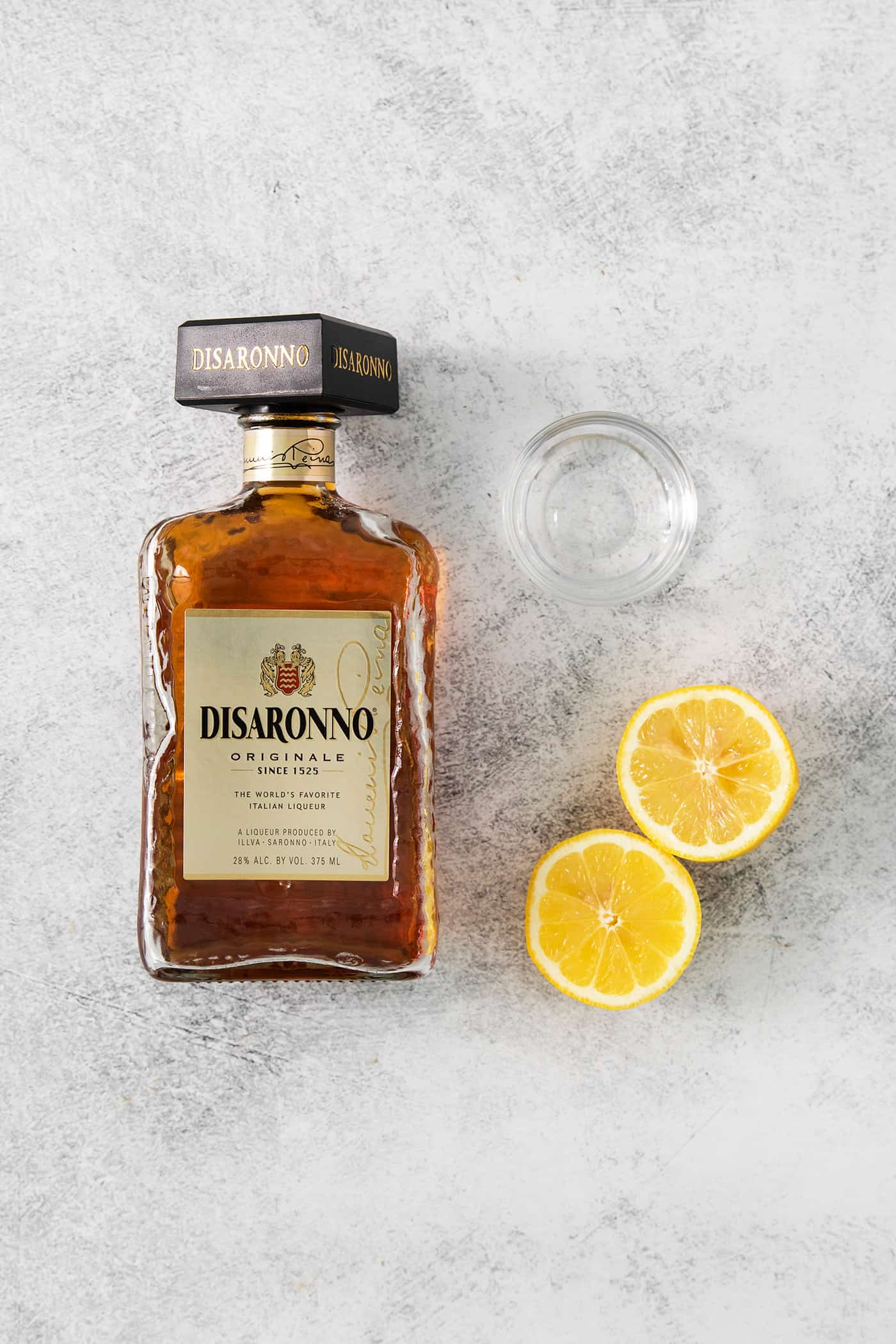 This Amaretto Sour is a classic cocktail featuring sweet almond-flavored amaretto liqueur and tart fresh lemon juice for a flavorful drink. The ingredients for amaretto sour are shown portioned out: amaretto, lemons, and simple syrup.
