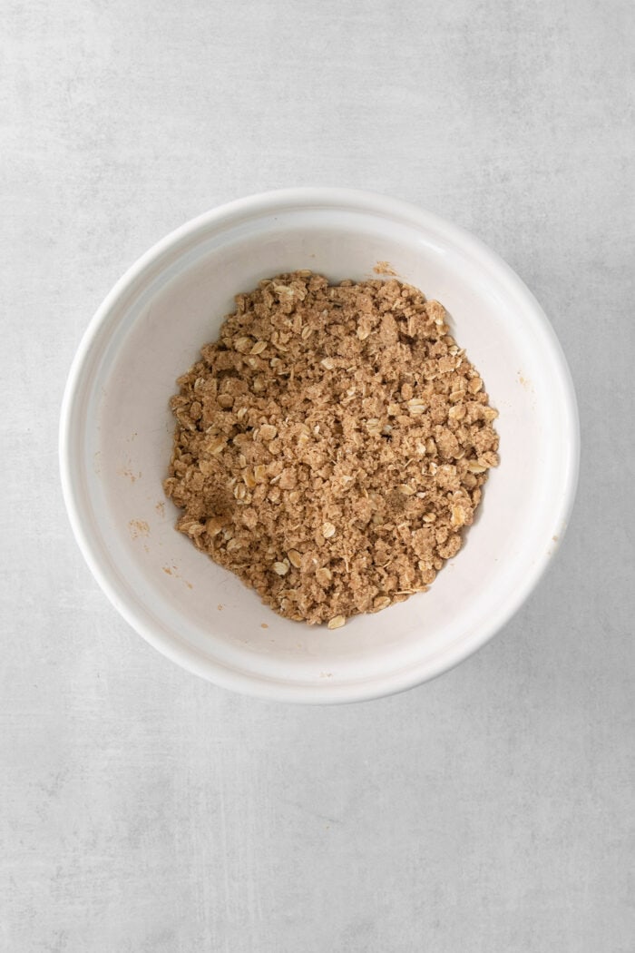 A white bowl of streusel for banana coffee cake.