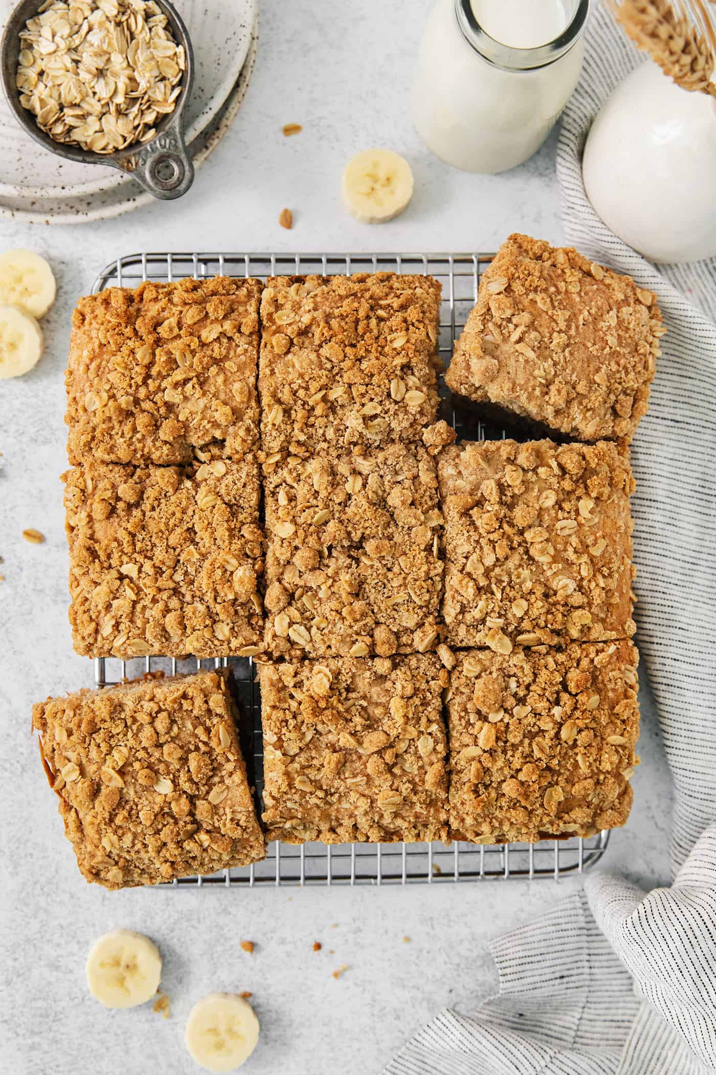 Banana coffee cake is cut into 9 squares with banana slices scatted around them.