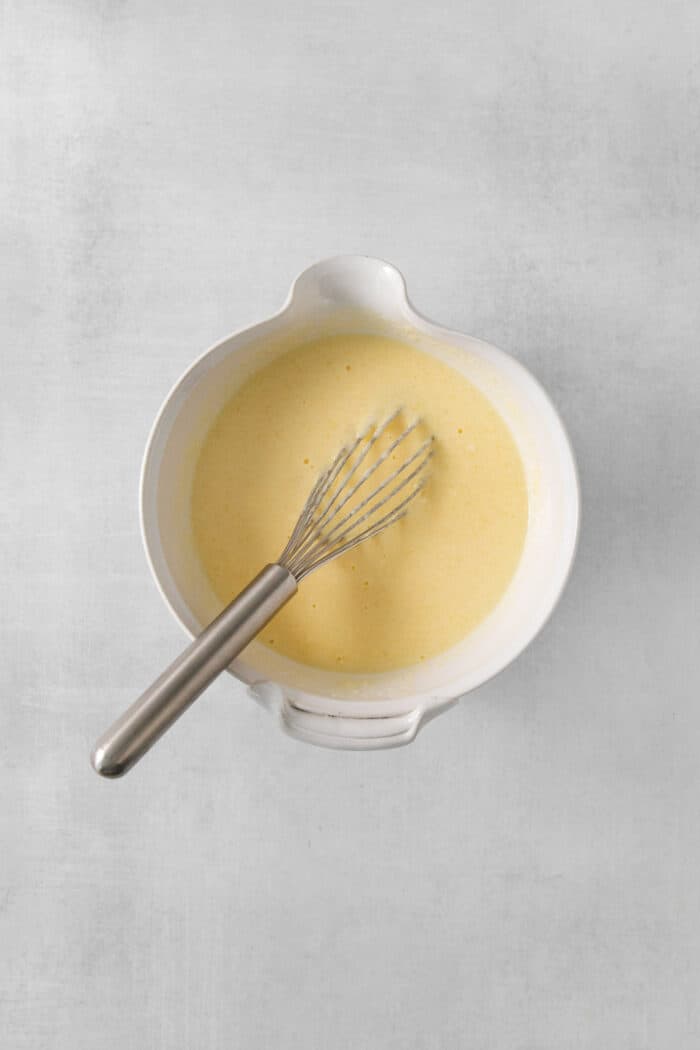 A whisk in a white bow, of cottage cheese pancake batter.
