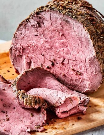 roast beef on a wood cutting boards, with some of it sliced