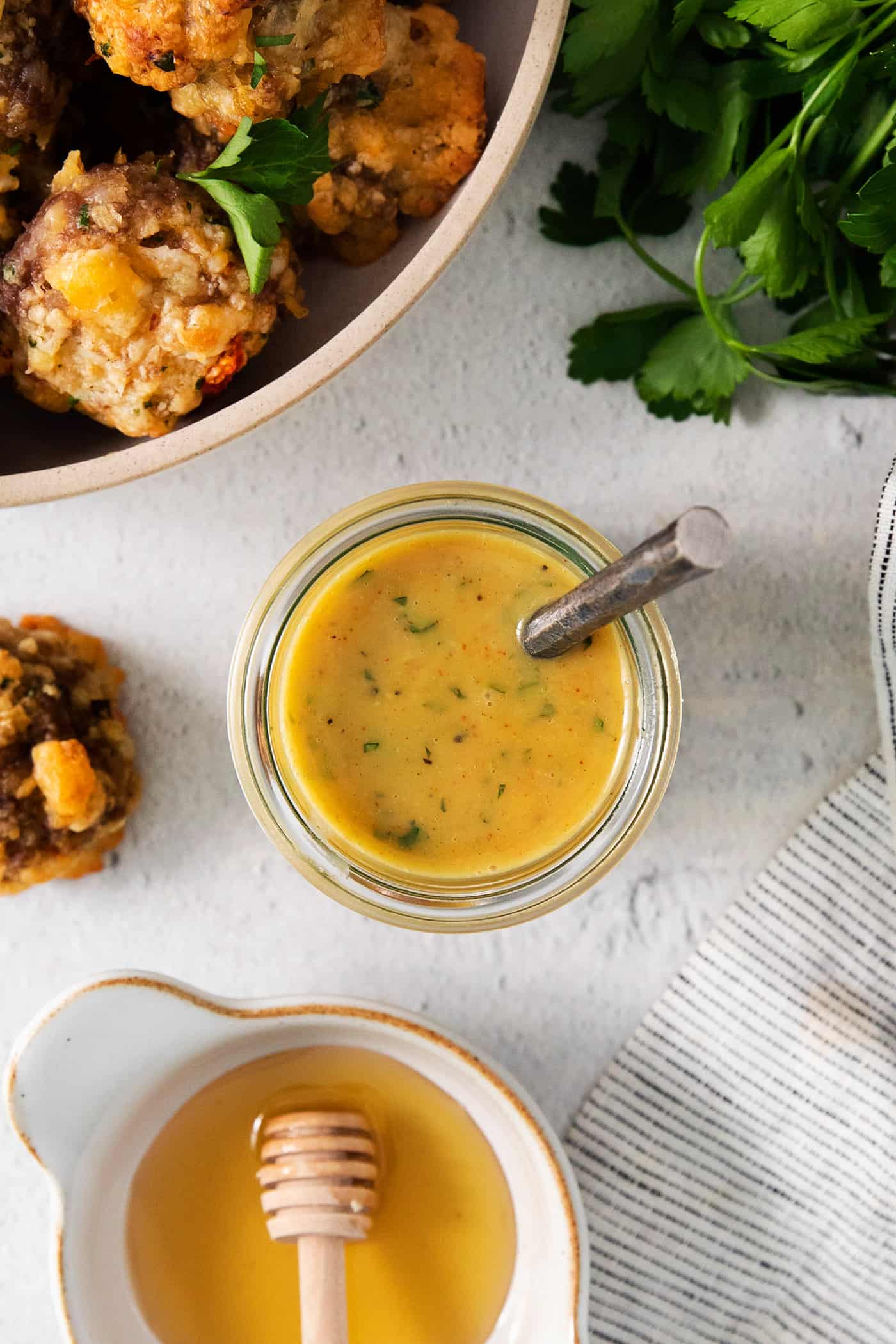 A top down view of a jar of honey mustard dip, sausage cheese balls, and a bowl of honey.