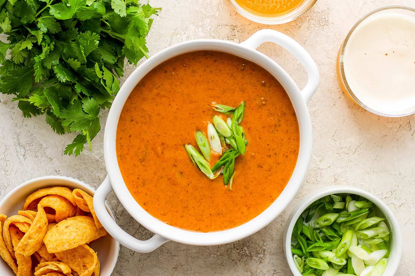 A white serving dish of chili cheese dip garnished with green onions.