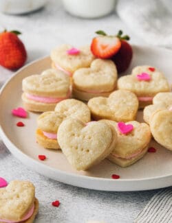 Heart-shaped strawberry cream wafer cookies are displayed on a white plate.