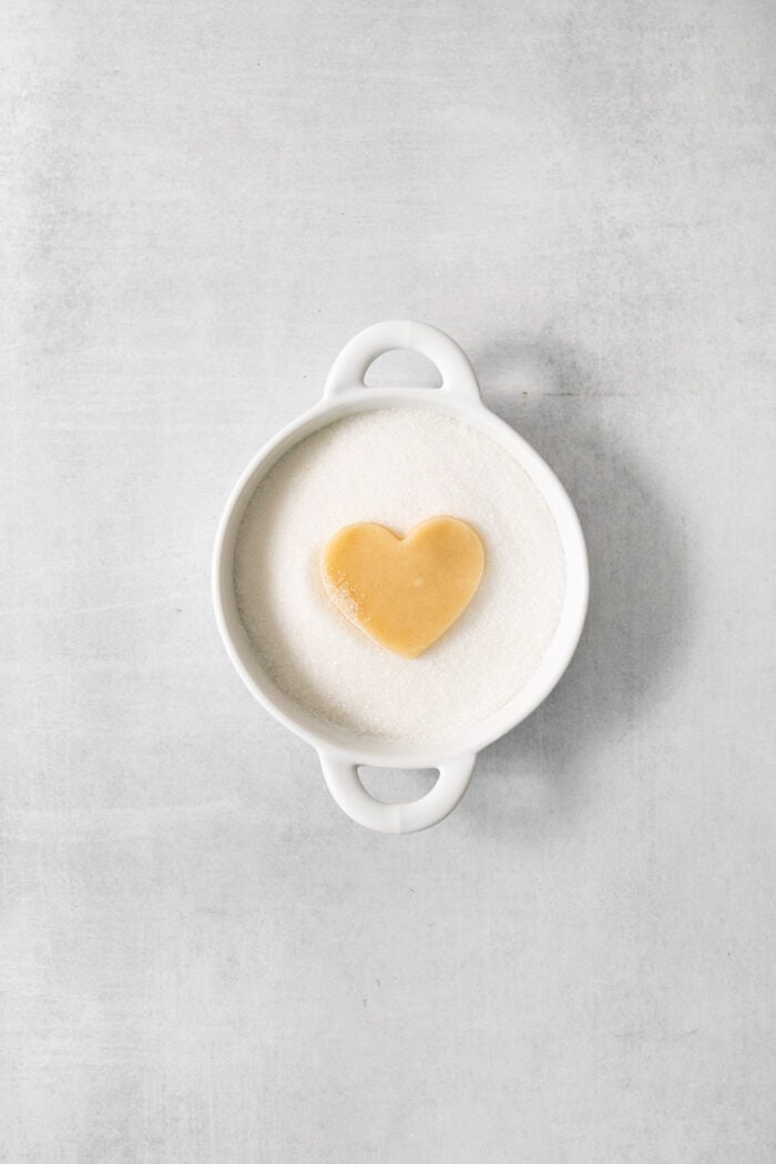 A heart shaped cream wafter cookie is dipped in sugar.