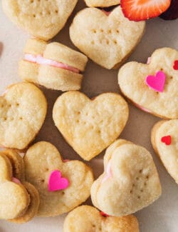 A close up of filled strawberry cream wafer sandwich cookies topped with heart sprinkles.