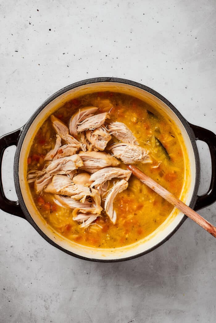 Shredded chicken is added back into the soup pot.