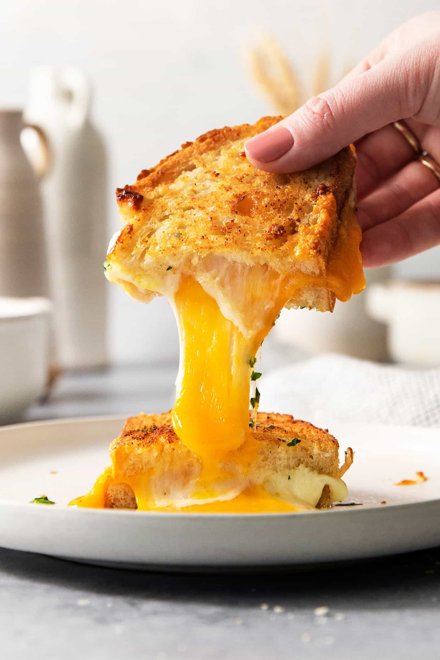 A hand pulls apart a piece of air fryer grilled cheese to show the melted cheese inside.