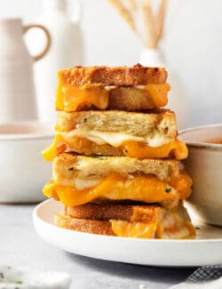 A stack of slices of air fryer grilled cheese sandwiches shows the melted cheese inside.
