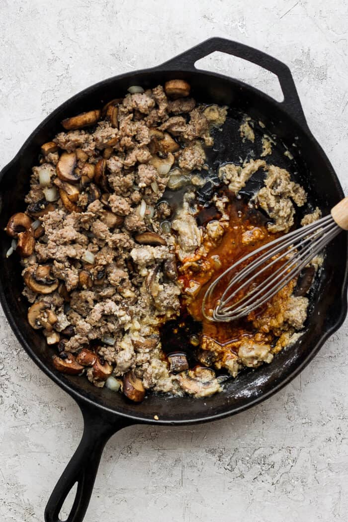 Hot sauce is whisked into the skillet of cooked vegetables and sausage.