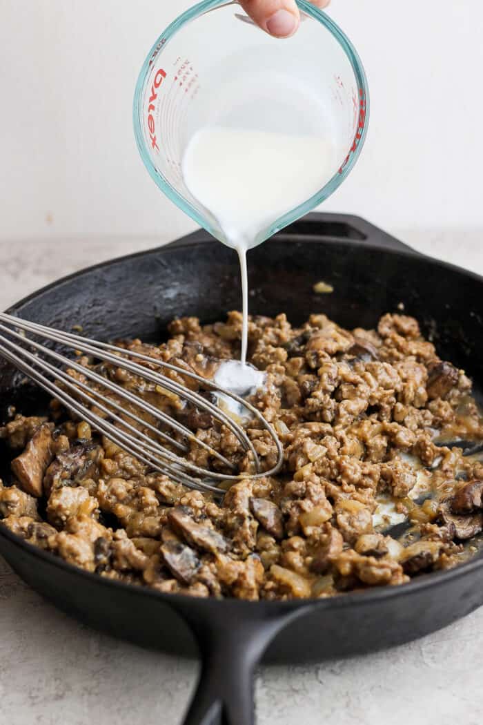 Milk is now poured into the skillet to be incorporated with a whisk.