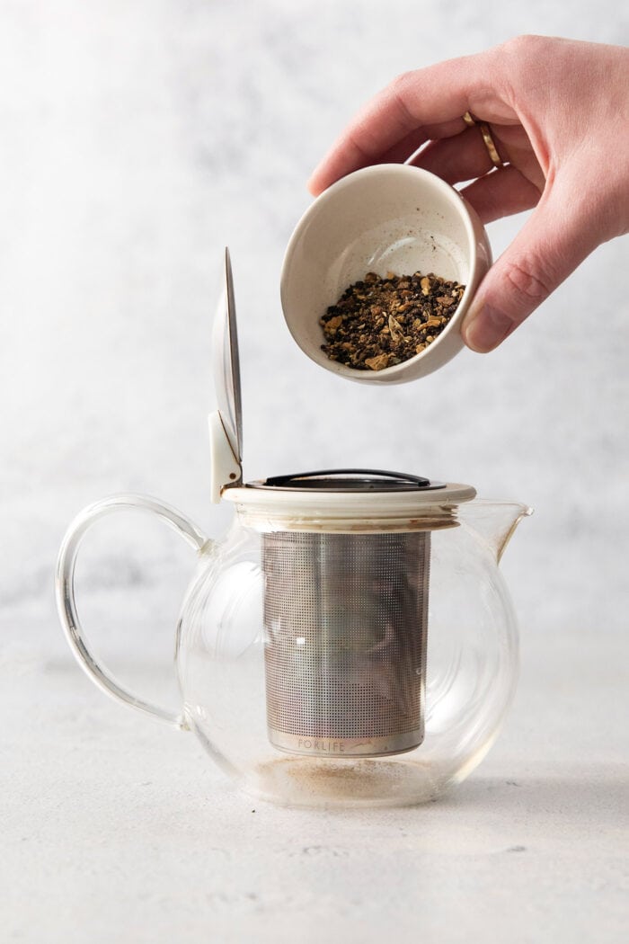 adding loose leaf tea to the strainer of a teapot