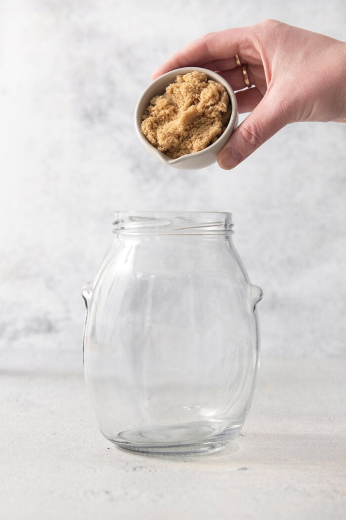 adding brown sugar to a large glass jar