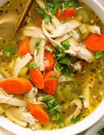 Chunks of chicken and vegetables are seen in a bowl of chicken noodle soup.