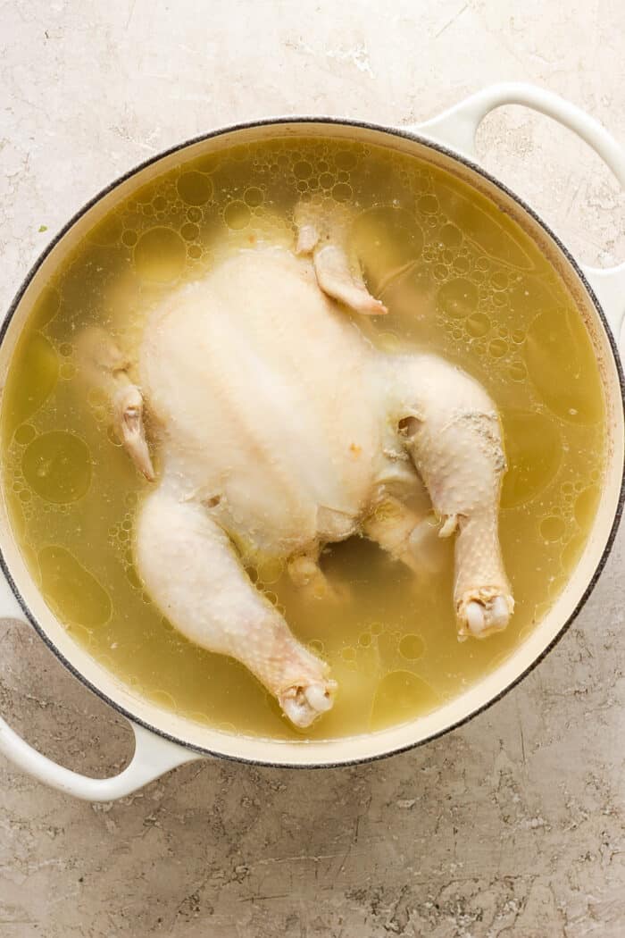 A whole chicken cooks in a pot for homemade chicken stock.
