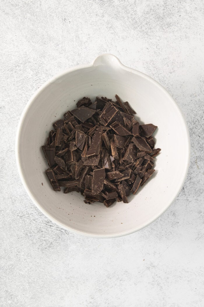 A white bowl full of chopped chocolate.