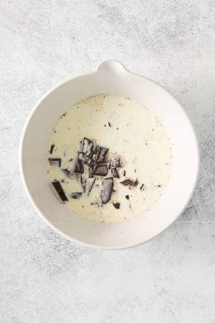 Chopped chocolate is added to a bowl of hot cream for chocolate ganache.