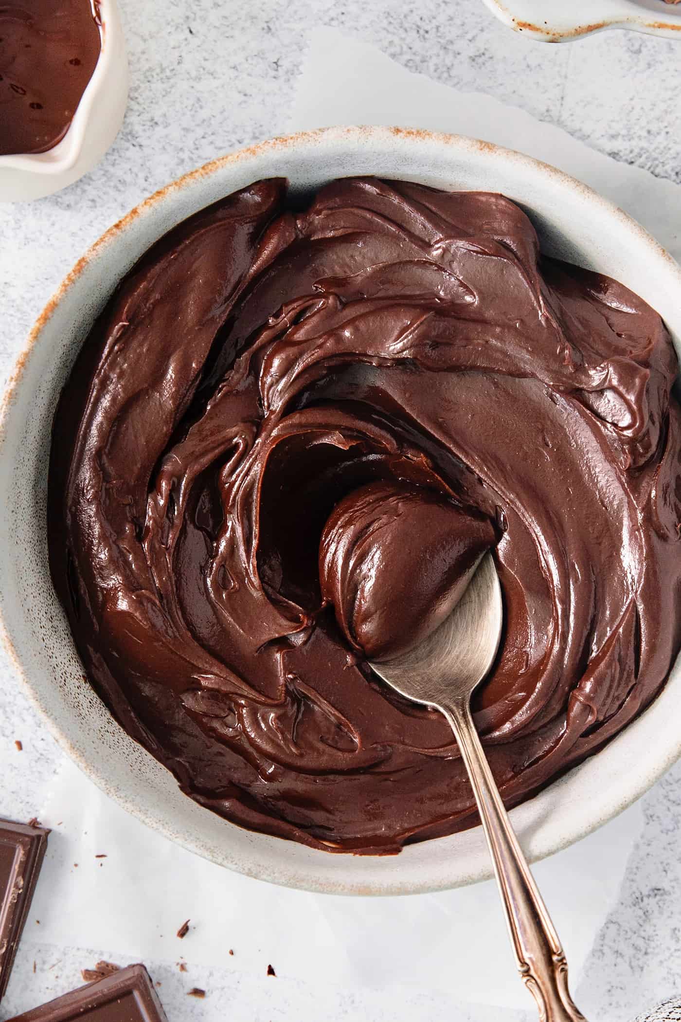 A spoon stirs a bowl of chocolate ganache.