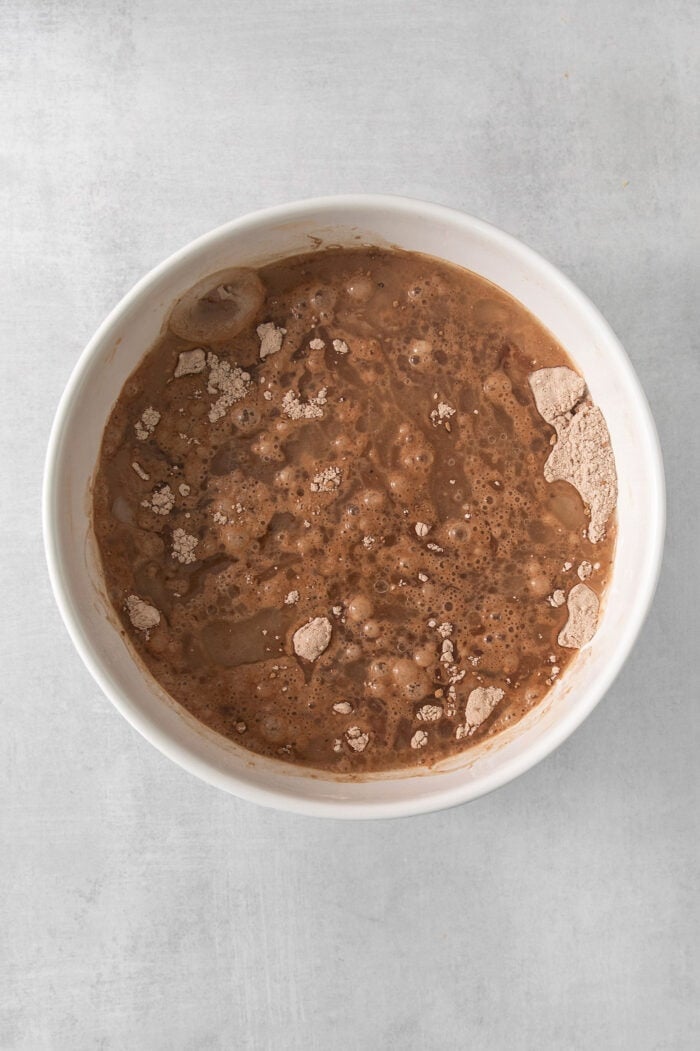 Chocolate cake batter is combined in a white bowl.