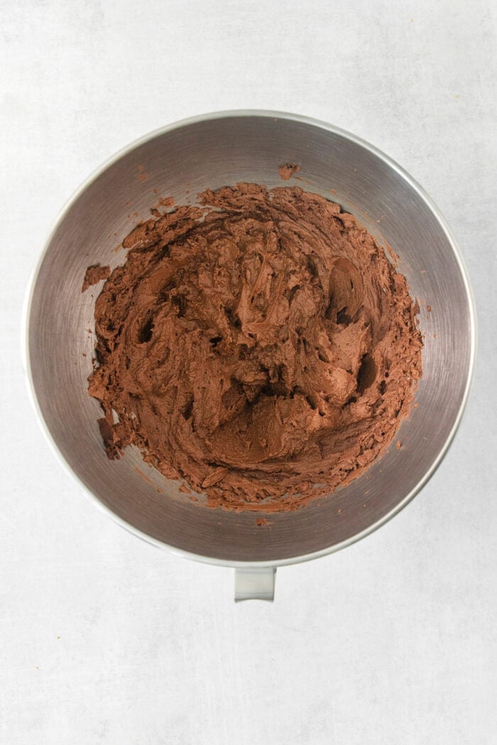 Whipped chocolate ganache frosting in a metal bowl.