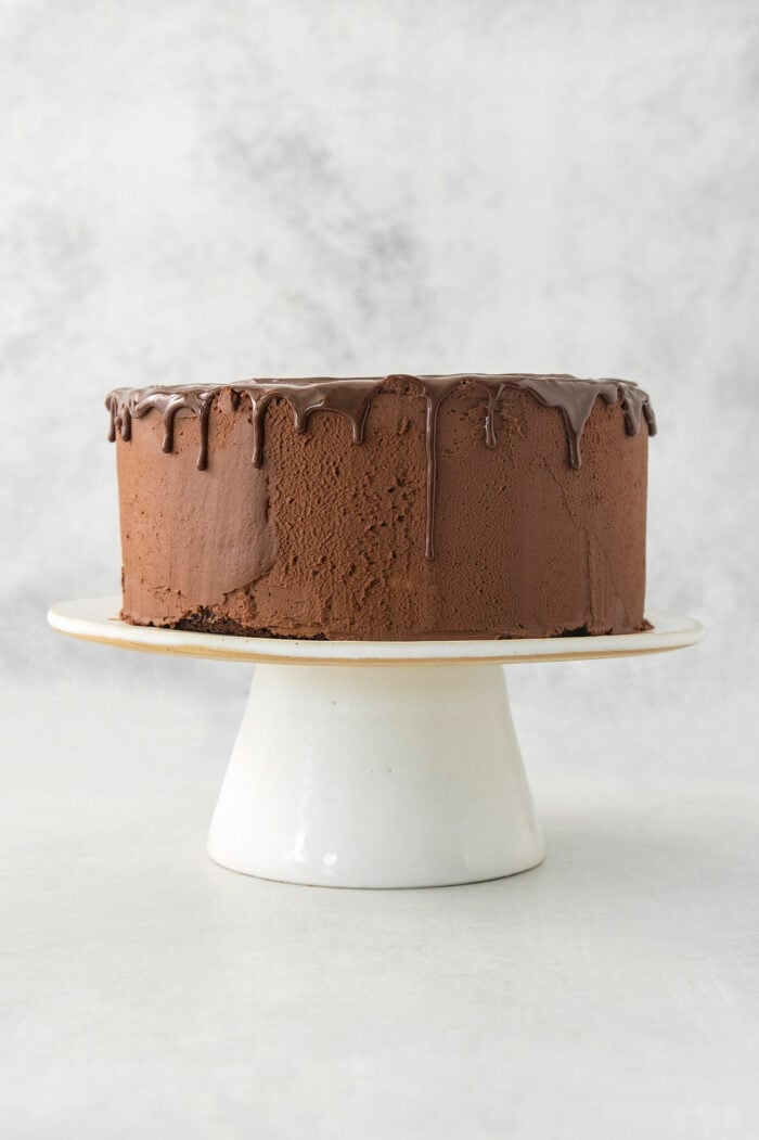 A side view of a chocolate ganache cake topped with chocolate drizzle.