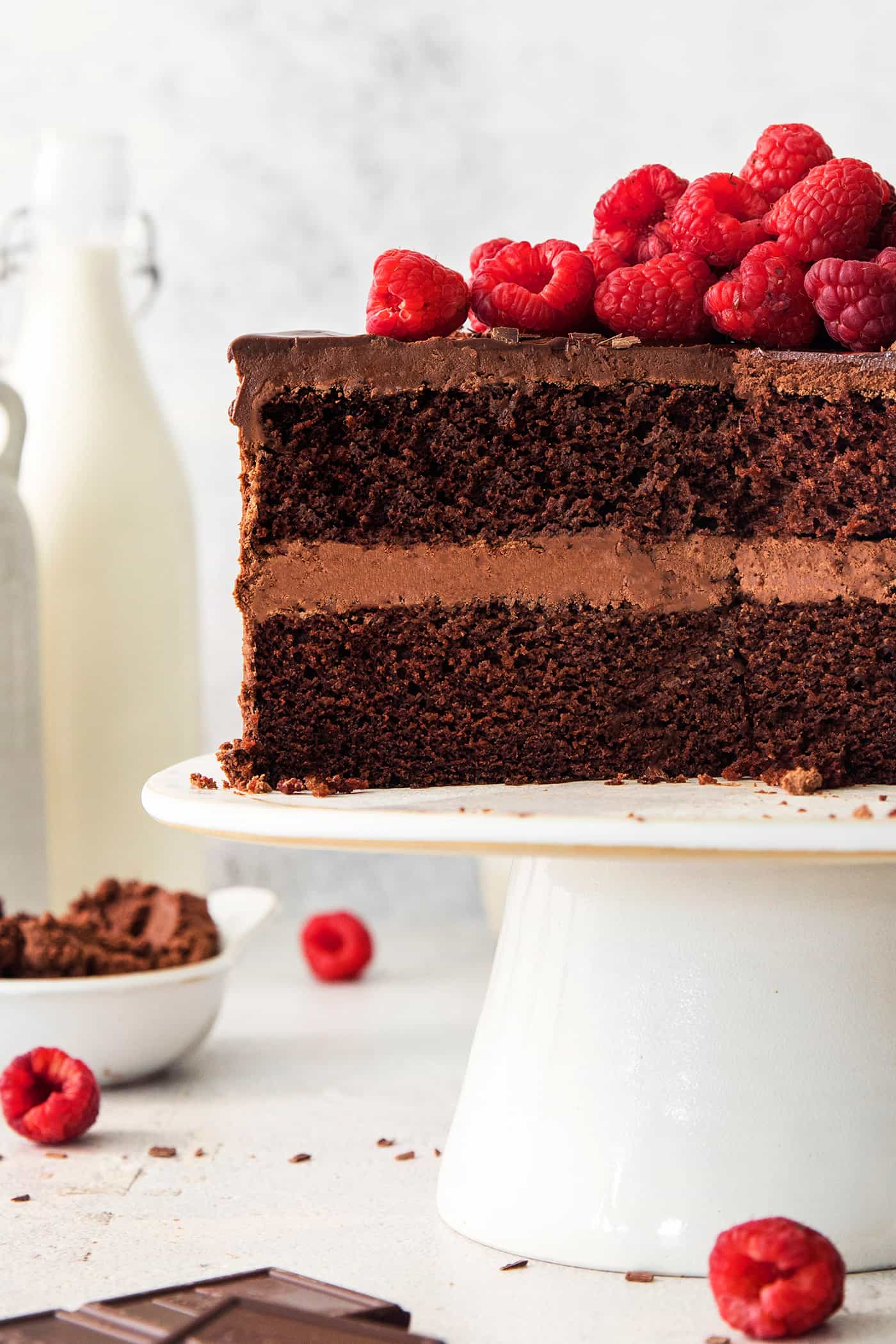 A side view of a cut chocolate ganache cake on a cake stand.