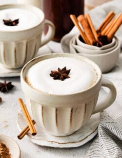 2 mugs of dirty chai latte and some cinnamon sticks