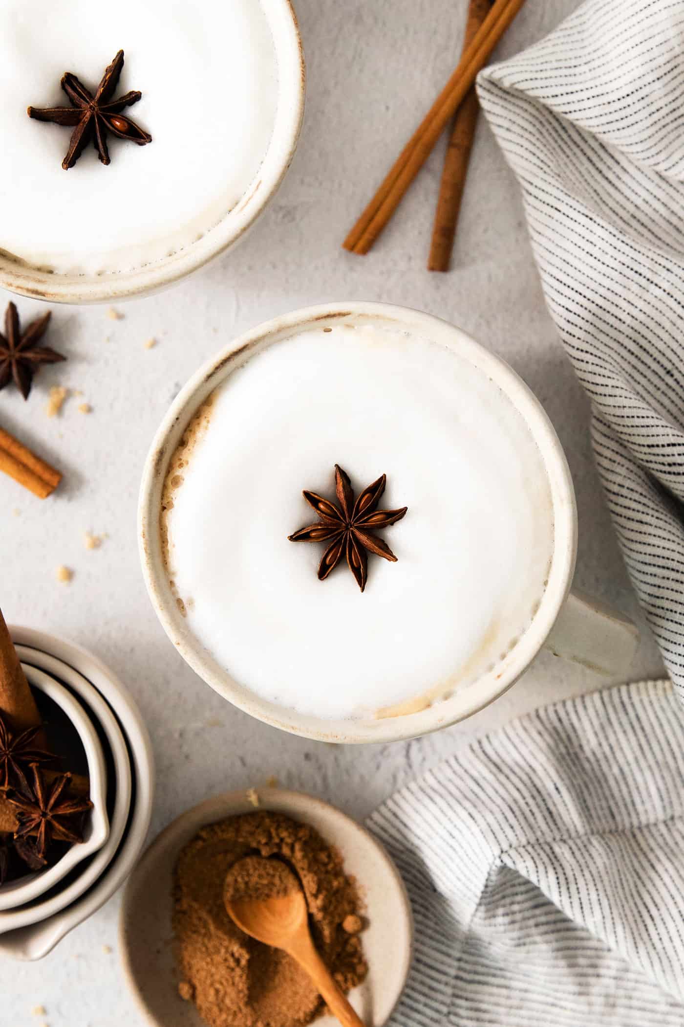 overhead photo of 2 lattes in mugs, with star anise floating on the frothed milk