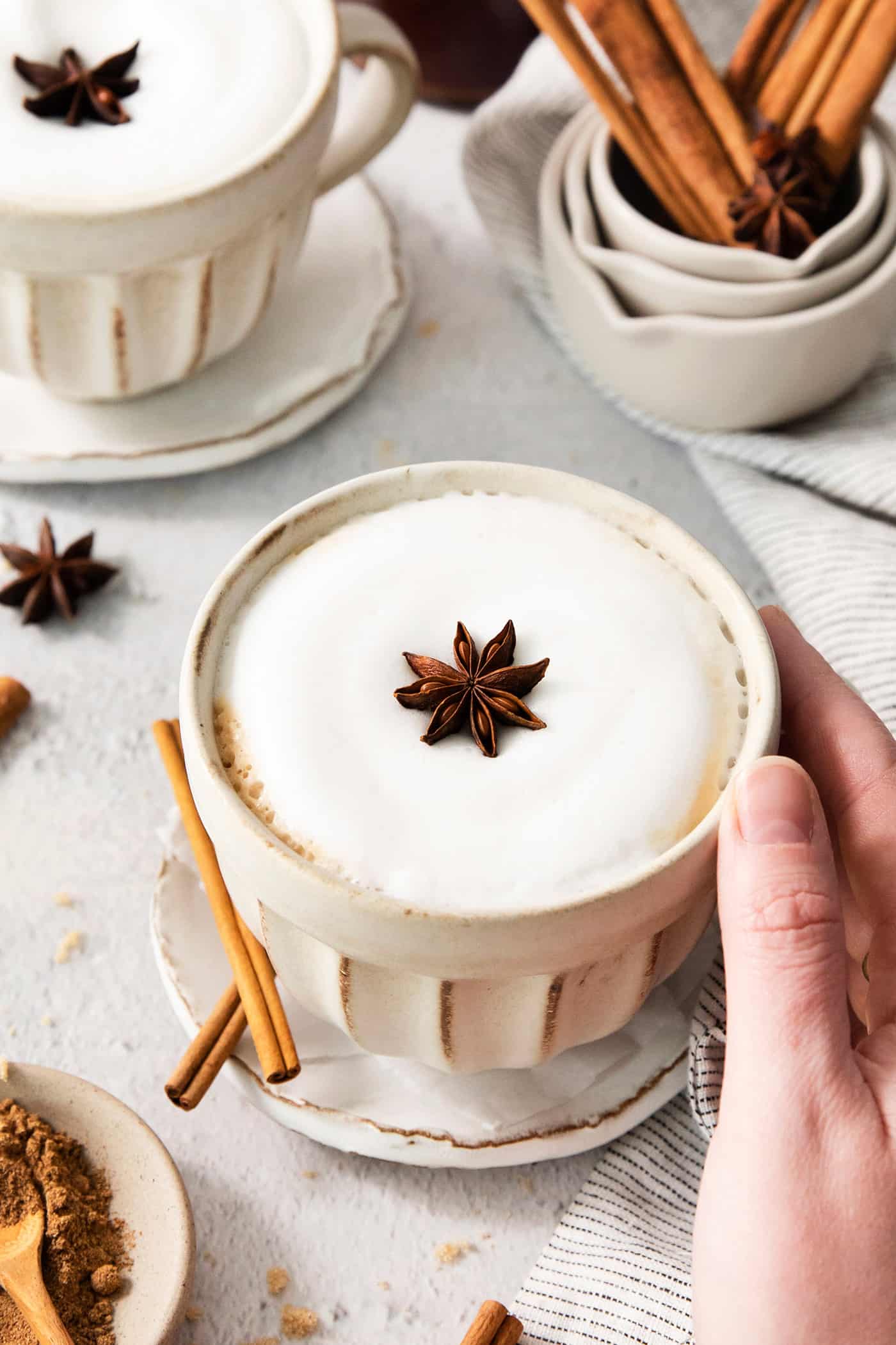 a hand holding a mug of dirty chai latte