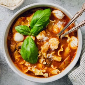 Fresh basil leaves garnish a bowl of slow cooker lasagna soup with chicken.