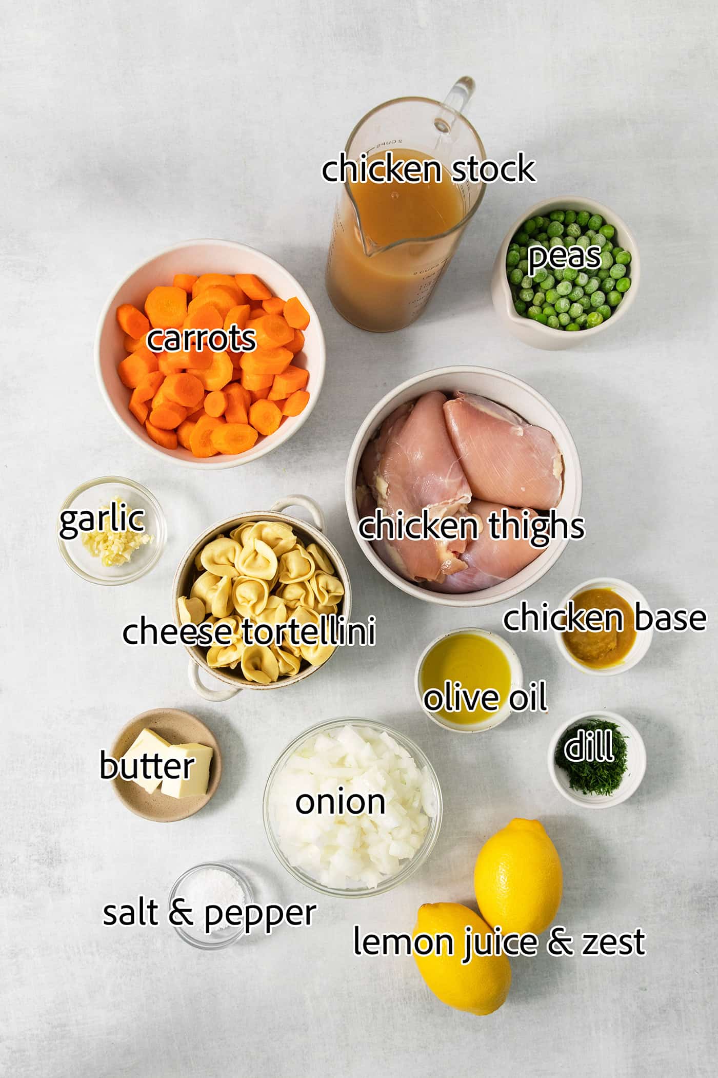The ingredients for lemon chicken tortellini soup are shown: chicken, carrots, broth, peas, olive oil, garlic, herbs, salt and pepper, lemon, tortellini.