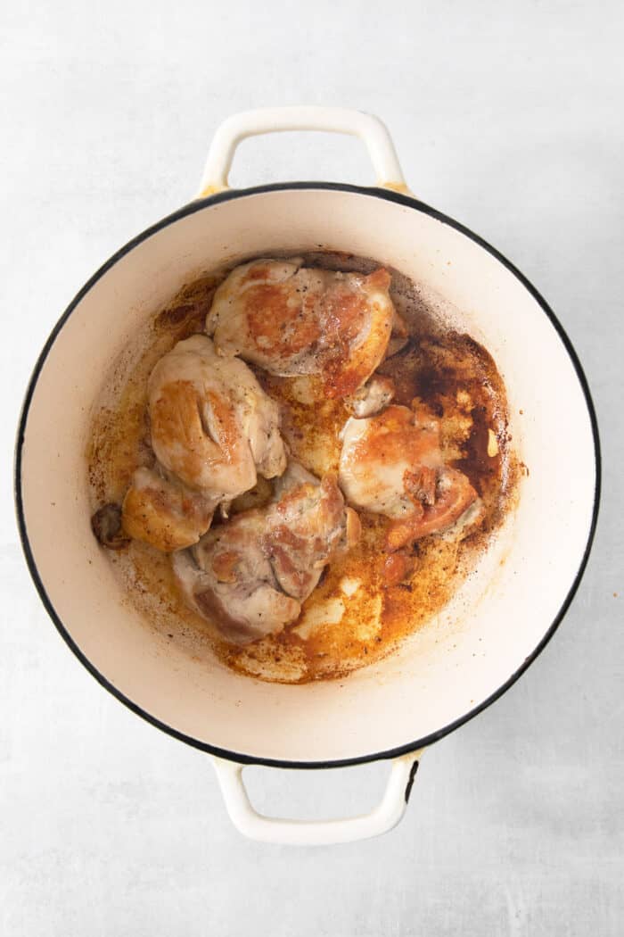 Chicken thighs cook in a pot for soup.