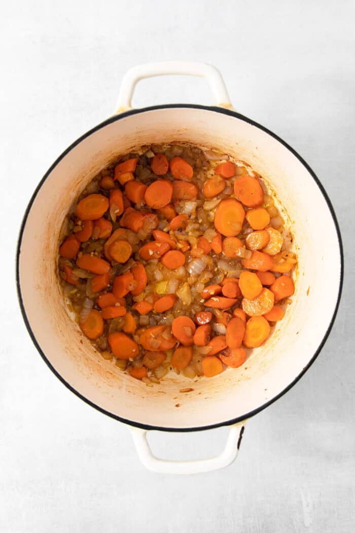 Carrots, onions, and garlic cook in a large pot.