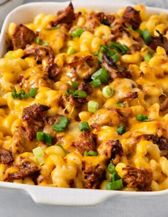 A green onion-topped casserole dish full of cooked pulled pork mac and cheese.