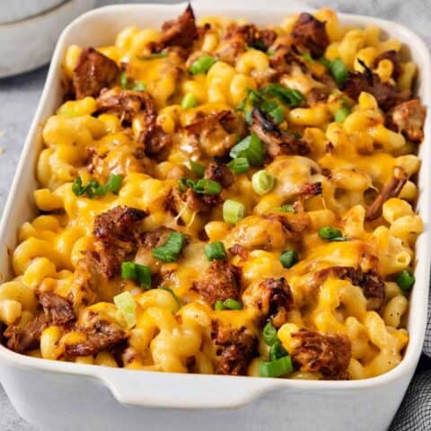 A green onion-topped casserole dish full of cooked pulled pork mac and cheese.