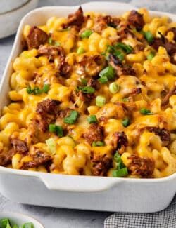 A green onion-topped casserole dish full of cooked pulled pork mac and cheese.