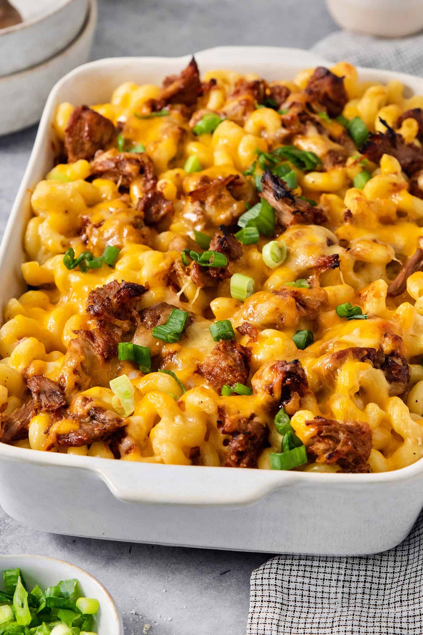 A green onion-topped casserole dish full of cooked pulled pork mac and cheese.