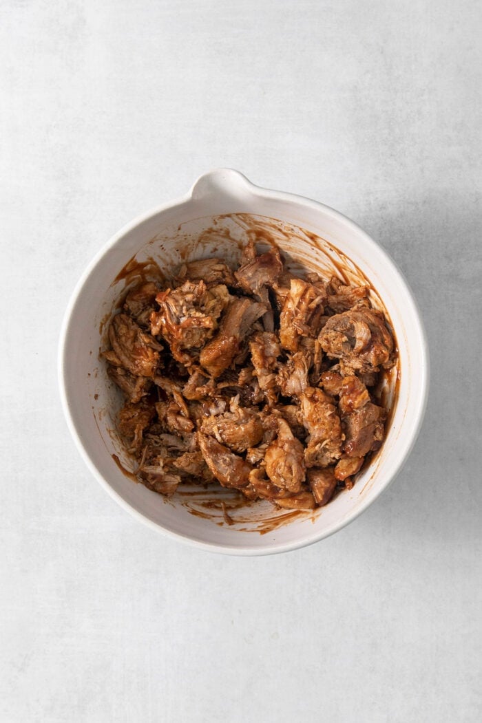 A white bowl full of pulled pork.