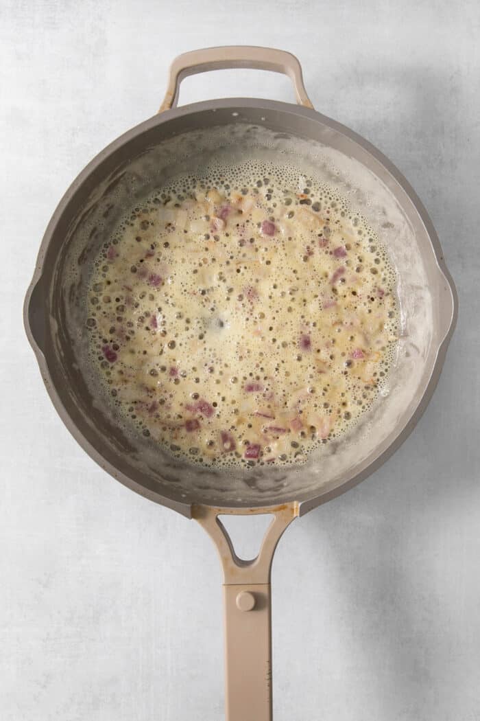 Butter is added to a skillet of onions.